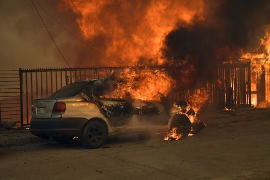 18일(현지시간) 칠레 비오비오주 콘셉시온에서 주택과 자동차가 불길에 휩싸여 있다. AFP연합뉴스