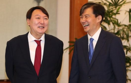 2019년 7월 25일 윤석열 신임 검찰총장(왼쪽)과 조국 민정수석이 윤 총장에 대한 임명장 수여식 직전 환담하면서 웃고 있다. 이에 앞서 검찰총장 후보자 4명에 대한 면접을 직접 진행한 조국 민정수석은 다른 3명의 후보자와 달리 수사·기소 분리, 공수처 설치 등 검찰개혁에 매우 적극적인 윤석열 후보자를 보며 오히려 진정성을 의심했다고 말했다. / 청와대사진기자단