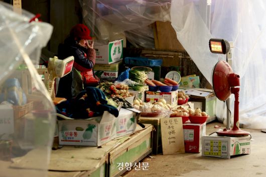 한파가 연일 이어지고 있는 21일 서울 서대문구 인왕시장에서 상인이 전기 난방기구로 추위를 녹이고 있다. 2026.01.21 문재원 기자