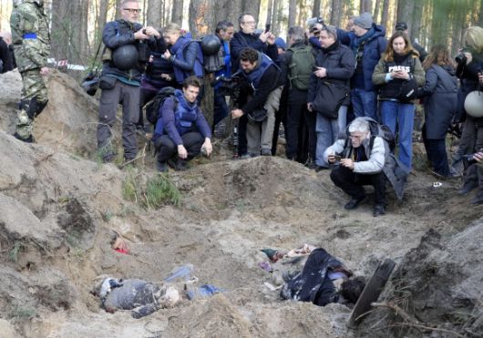 우크라이나 수도 키이우 근교 모티진 마을 외곽에서 4일(현지시간) 발견된 일가족 매장지 모습을 취재진들이 카메라에 담고 있다. 희생자는 마을 촌장과 그녀의 남편, 아들이다.키이우 로이터 연합뉴스