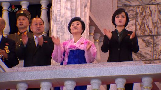 손뼉치며 열병식 행사 지켜보는 리춘히와 김옥주 - 한복을 입은 리춘히 아나운서와 ‘인민배우’ 칭호를 받은 가수 김옥주가 손뼉을 치며 행사를 지켜보고 있다. 리 아나운서는 녹화 중계된 이날 행사의 TV 방송 해설을 맡기도 했다. 조선중앙TV 화면 2021.9.9