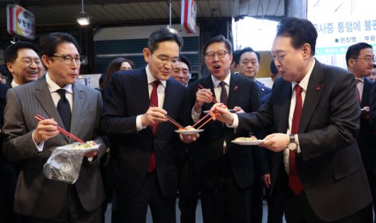 윤석열 대통령이 6일 부산 중구 깡통시장에서 재계 총수들과 분식을 맛보며 이재용 삼성전자 회장, 조현준 효성그룹 회장에게 빈대떡을 나눠주고 있다.  2023.12.6 연합뉴스
