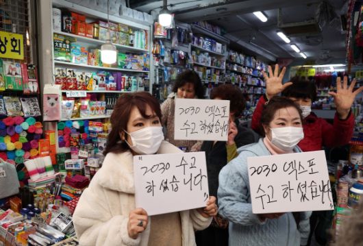 윤석열 대통령의 방문을 앞두고 6일 부산 중구 깡통시장에서 부산 시민들이 윤 대통령의 부산엑스포 유치활동에 대한 감사 메시지를 보여주며 환영하고 있다.  2023.12.6 연합뉴스