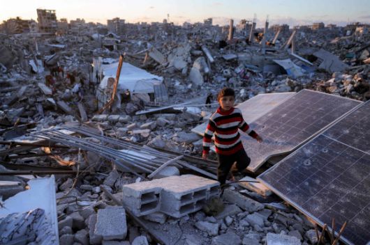 가자지구 북부 자발리아의 잔해 속에서 한 소년이 깨진 태양광 패널을 지나가고 있다.  2025.4.15 AFP 연합뉴스