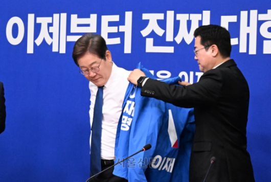 박찬대 더불어민주당 당대표 직무대행 겸 원내대표가 28일 국회에서 열린 당 최고위원회의에서 이재명 대선 후보에게 선거운동용 파란색 점퍼를 입혀주고 있다. 2025.4.28 안주영 전문기자