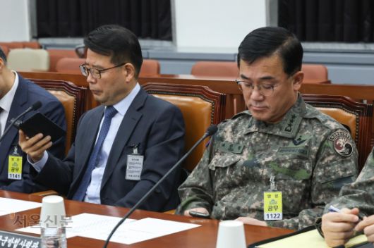 여인형 전 국군방첩사령관과 윤오준 국정원 제3차장이 7일 국회 정보위원회에서 열린 비상계엄 관련 긴급 현안질의에서 회의 시작 전 윤석열 대통령의 대국민 담화를 보고 있다. 2024.12.7 국회사진기자단