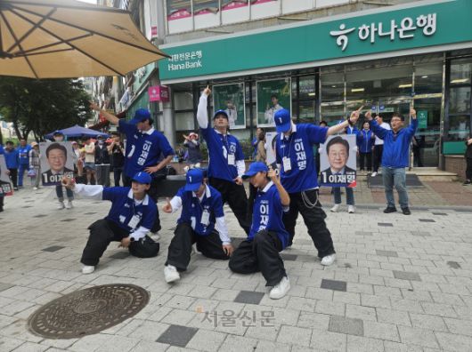 더불어민주당 2030 청년 선거운동원인 시너지유세단이 21일 경기 광명시의 한 인도에서 ‘기호 1번’ 손동작을 취하며 선거유세 무대를 하고 있다. 박상연 기자