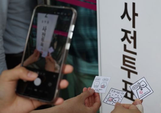 제21대 대통령선거 사전투표 첫날인 29일 서울 강남구 삼성2동주민센터에 마련된 사전투표소 앞에서 시민들이 투표 도장이 찍힌 그림을 들고 기념 촬영을 하고 있다. 2025.5.29 연합뉴스