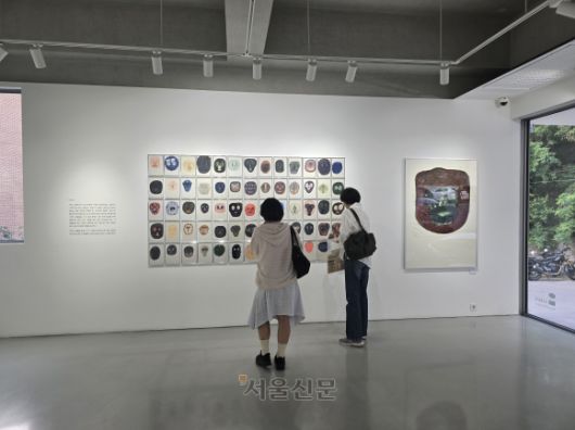 크라우더의 ‘얼굴들’ 연작을 감상하는 관람객의 모습. 이 작품은 그림책의 경계를 넘어 현대 미술로 확장한 크라우더의 예술적 도전을 보여 준다.