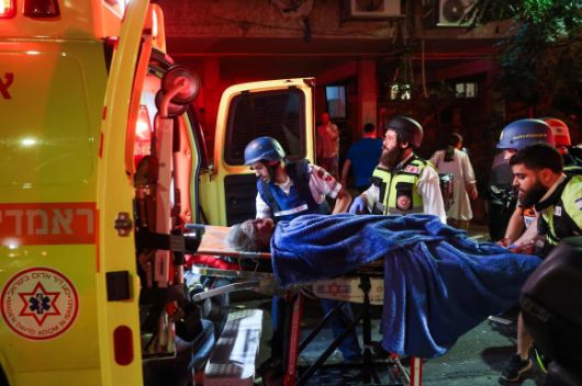 이스라엘 응급 구조대원들이 2025년 6월 13일(현지시간) 텔아비브 외곽 라맛간에서 이란에서 발사된 미사일에 맞은 현장에서 부상당한 주민을 이송하고 있다. AFP 연합뉴스