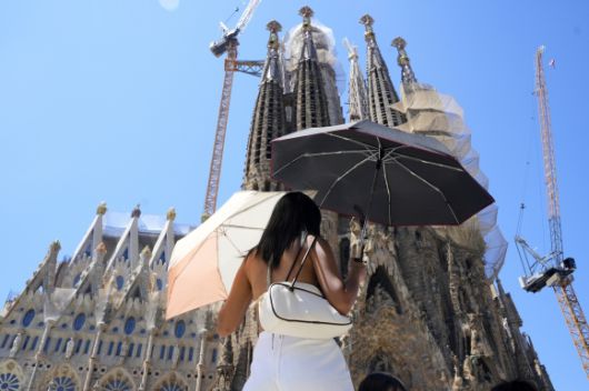 28일(현지시간) 스페인 바르셀로나에서 폭염이 기승을 부리고 있는 가운데 한 관광객이 사그라다 파밀리아 앞에서 양산 2개로 햇빛을 가리고 있다. 올 여름 첫 폭염이 스페인을 강타할 것으로 예상됨에 따라 스페인 곳곳에 폭염 경보가 내려졌다. 2025.6.28. EPA 연합뉴스