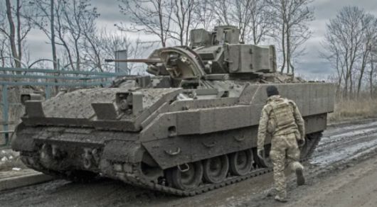 2023년 12월 4일 우크라이나 돈바스 전선에서 미국산 M2 브래들리 장갑차 옆에 서 있는 우크라이나 군인의 모습. 게티이미지/멀티비츠