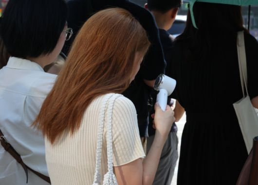 오늘도 덥다 더워 - 폭염이 이어지고 있는 8일 서울 세종대로사거리 인근에서 한 시민이 손 선풍기를 틀고 더위를 식히며 출근길 발걸음을 재촉하고 있다. 2025.7.8 뉴시스