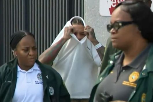 두 아이의 엄마인 전 여자친구를 폭행한 혐의로 11일(현지시간) 체포돼 조사를 받은 세계복싱협회(WBA) 라이트급 세계챔피언 저본타 데이비스가 옷으로 얼굴을 가린 채 터너길포드나이트 교정센터를 나서고 있다. 미국 CBS 보도화면 캡처