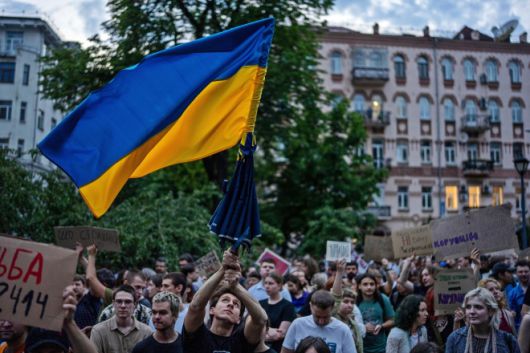 22일(현지시간) 우크라이나 수도 키이우 중심부에서 정부의 반부패 기관 독립성 훼손 법안에 반대하는 시위가 열린 가운데,  한 남성이 우크라이나 국기를 흔들고 있다. 2025.7.22 키이우 AP 연합뉴스