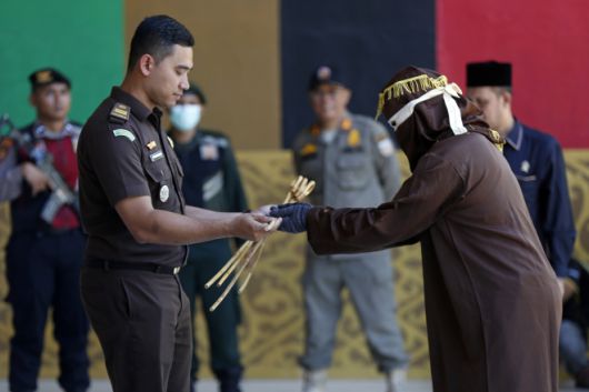 지난 26일(현지시간) 인도네시아 아체주 반다아체에서 진행된 태형 집행 현장에서 두건을 쓴 집행관이 등나무 지팡이를 받으며 매질을 준비하고 있다. 2025.8.26 EPA 연합뉴스