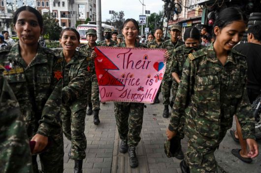 17일(현지시간) 네팔 카트만두의 마이티가르 만달라 공원에서 국가사관생도단(NCC)이 시위 중 숨진 72명의 희생자들을 기리는 ‘국가 애도일’ 추모 행진을 하는 가운데 한 생도가 ‘그들의 희생이 우리의 힘’이라고 적힌 추모글을 들어보이고 있다. 카트만두 AFP 연합뉴스