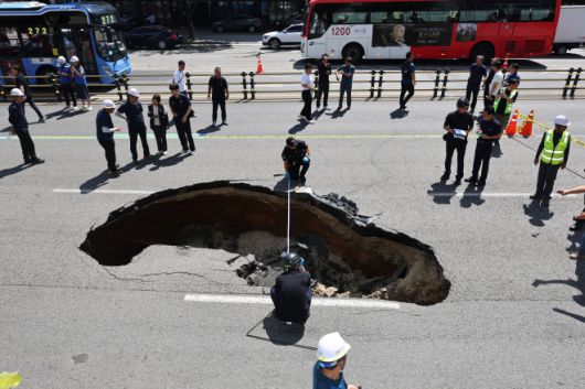 땅 꺼짐 사고 폭 깊이 측정하는 관계자들 - 29일 오전 서울 서대문구 연희동 성산로에서 발생한 땅 꺼짐(싱크홀) 현상 현장에서 경찰 및 소방 관계자들이 사고 폭 깊이를 측정하고 있다. 이 사고로 승용차 탑승자들이 병원으로 후송됐다. 2024.8.29 연합뉴스