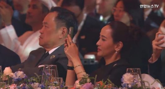 아누틴 찬위라꾼 태국 총리의 배우자 타나논 니라밋 여사가 31일 경북 경주 라한셀렉트호텔 대연회장에서 열린 ‘2025 APEC 정상회의’ 환영 만찬 공연 무대에 오른 가수 지드래곤을 휴대폰 카메라로 촬영하고 있다. 2025.10.31 연합뉴스TV 화면