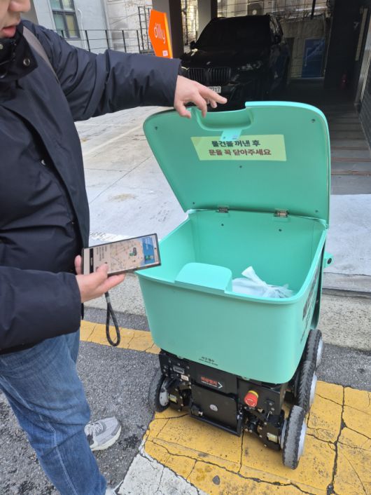 13일 서울 논현동에서 소비자가 배달로봇 딜리에서 주문한 물품을 수령하고 있다. 김현이 기자