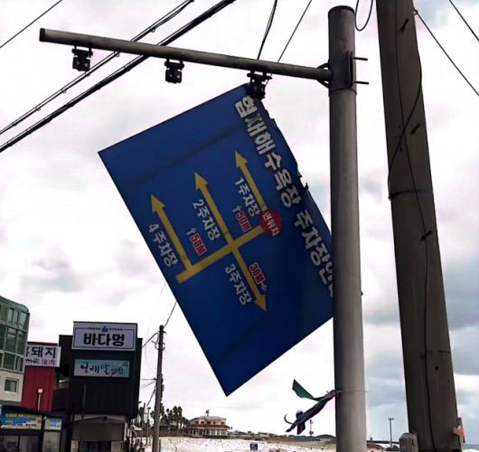 제주시 한림읍 협재리 해안을 순찰하던 해안1경비대 직원들이 22일 강풍에 연결고리가 떨어져 5m 높이에서 흔들리던 철재 소재의 대형 교통안내표지판을 떼어내 안전조치를 취했다. 제주경찰청 제공