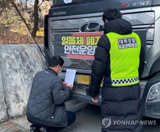 멈춰 선 화물차에 업무 개시 명령서를 부착하고있다