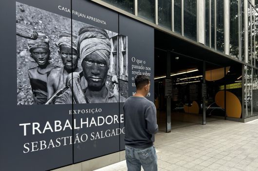 2025년 5월30일 브라질 리우데자네이루에서 열린 세바스치앙 살가두의 ‘노동자’ 전시회를 알리는 입간판 앞을 한 사람이 지나가고 있다. 이 전시는 그의 삶과 작업을 기리는 유작 전시가 됐다. EPA 연합뉴스