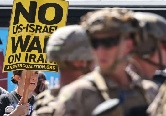 ‘대이란 전쟁’과 이민자 단속에 반대하는 시위대가 2025년 6월22일(현지시각) 미국 캘리포니아주 로스앤젤레스에서 미 해병대가 지키는 연방 건물 주변에서 팻말을 들고 행진하고 있다. 사진 AFP 연합뉴스