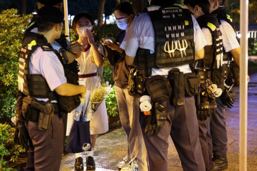 2025년 6월4일 홍콩 빅토리아공원 부근에서 꽃을 든 한 학생이 경찰의 검문을 받고 있다. REUTERS