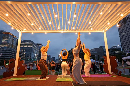 7월4일 저녁 서울 종로구 세종로 광화문광장에서 외국인을 위한 영어 요가가 열리고 있다. 강사들이 연단에 올라 자세를 취하고 있다.