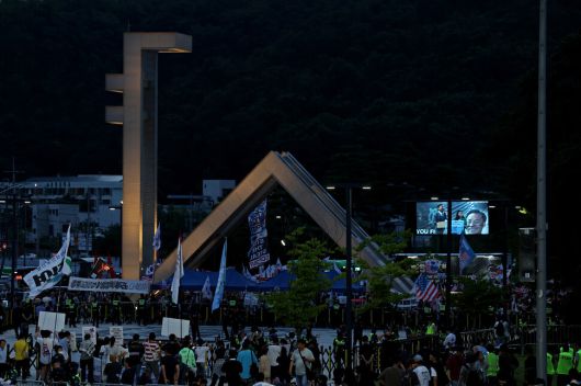 ‘샤’ 자 형태의 서울대 정문에 불을 밝힌 채 ‘사기꾼 모스 탄 방한 반대 대학생 긴급행동’(아래쪽)이 교문 앞에서 특강을 하는 탄 교수를 규탄하고 있다.