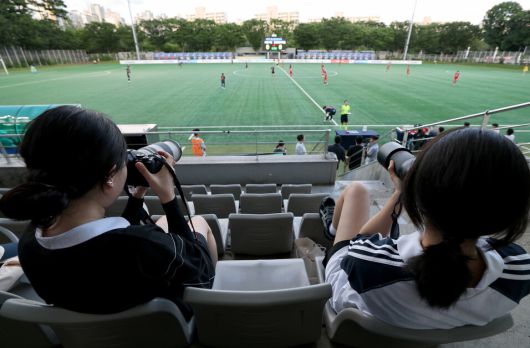 WK리그 경기 직관이 네 번째라는 최예슬(23·왼쪽)씨가 2025년 7월21일 저녁 서울 마포구 상암동 서울월드컵경기장 보조경기장에서 열린 서울시청 아마조네스(검은색 유니폼)와 인천현대제철 레드엔젤스WFC의 경기를 사진에 담고 있다. 이종근 선임기자 root2@hani.co.kr