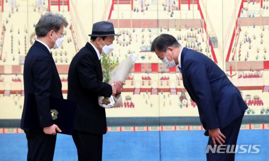 [서울=뉴시스]추상철 기자 = 문재인 대통령이 15일 오전 청와대 본관에서 권칠승 중소벤처기업부 장관 부친에게 꽃다발을 전달한 후 인사하고  있다. 2021.02.15. scchoo@newsis.com