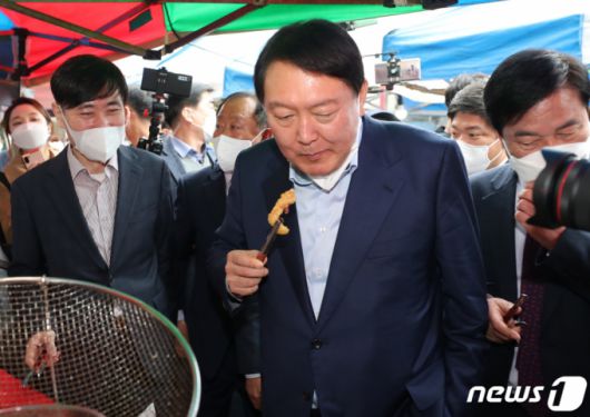 (포천=뉴스1) 구윤성 기자 = 윤석열 국민의힘 대선 경선후보가 4일 오후 경기 포천 소흘읍 송우리시장을 방문해 오징어튀김을 먹고 있다. 2021.11.4/뉴스1