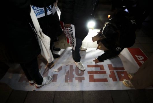 전국민중행동 관계자 및 시민들이 30일 오후 서울 중구 파이낸스빌딩 앞 계단에서 열린 박근혜사면반대, 문재인정부규탄 시민발언대에서 박근혜 사면이라고 적힌 현수막을 밟고 있다. /사진제공=뉴시스