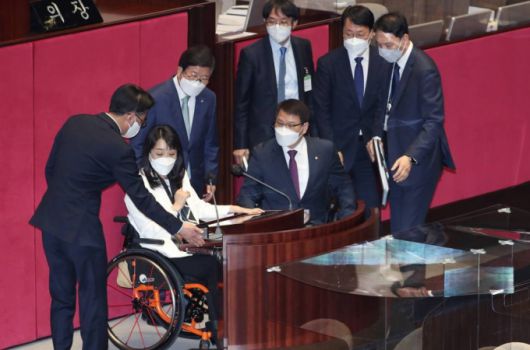 최혜영 더불어민주당 의원이 5일 오후 국회 본회의장에서 발언대로 나와 휠체어 이용자 편의를 고려한 발언대 높이 조절 등을 테스트해 보고 있다. 박병석 국회의장 등 국회 관계자들이 두 의원의 의견을 청취하고 있다. / 사진제공=뉴시스