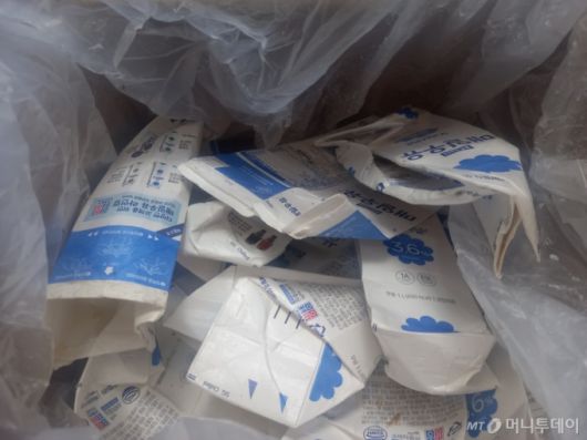 지난 13일 경기도 하남의 폐우유팩 집하장에서 비닐봉투를 여니 파리떼가 솟아올랐다. 우유팩들이 아무렇게나 꾸겨져 있었다. 모 프랜차이즈 카페에서 가져온 폐우유팩들이었다. 세척도, 정돈도 안된 우유팩은 보관 과정에 썩어 재활용하기도 전에 폐기되기 일쑤다./사진=김성진 기자.