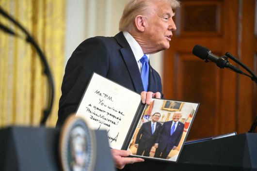 도널드 트럼프 미국 대통령이 7일(현지시각) 미국 워싱턴DC 백악관에서 진행된 이시바 시게루 일본 총리와 정상회담 후 공동 기자회견에서 함께 찍은 사진에 사인을 한 뒤 선물하고 있다. /AFP=뉴스1