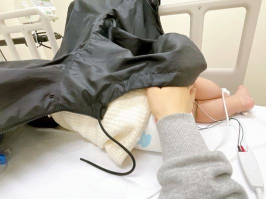 심전도 측정 기기를 몸에 달고 누워있는 아기. 응급실 조명 조절이 어려워 점퍼로 얼굴을 덮어 놓았다. /사진=최우영 기자