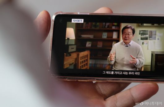 (서울=뉴스1) 장수영 기자 = 10일 오전 서울 중구 서울역을 찾은 시민이 스마트폰을 통해 이재명 전 더불어민주당 대표의 대통령 선거 출마 선언 영상을 바라보고 있다. 2025.4.10/뉴스1  Copyright (C) 뉴스1. All rights reserved. 무단 전재 및 재배포,  AI학습 이용 금지. /사진=(서울=뉴스1) 장수영 기자