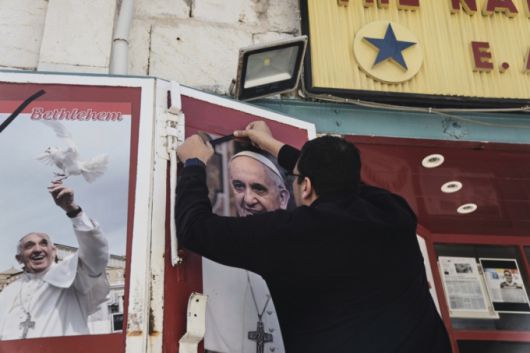 프란치스코 교황이 선종한 21일 팔레스타인 서안지구 베들레헴에서 한 상점 주인이 프란치스코 교황의 사진에 검은 리본을 달고 있다. /AP=뉴시스