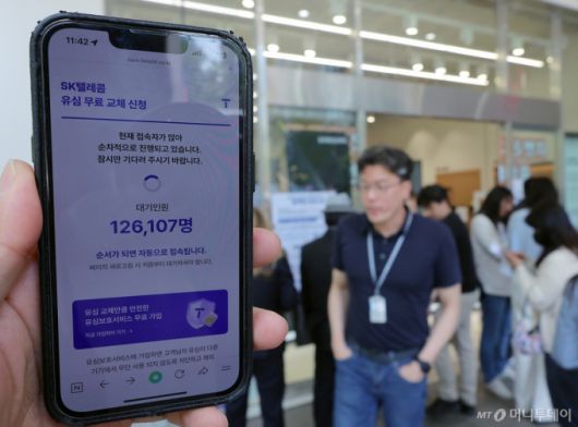 해킹 공격으로 가입자 유심 정보가 탈취된 SK텔레콤이 가입자 유심 무상 교체를 시작한 28일 오전 서울 종로구 T월드 매장 앞에서 직원들의 안내를 받아 온라인 예약을 하고 있다.  /사진=뉴스1