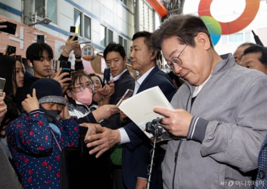 (양양=뉴스1) 이재명 기자 = '골목골목 경청투어 : 동해안벨트편'에 나선 이재명 더불어민주당 대통령 후보가 3일 오전 강원 양양군 양양시장에서 한 시민 요청으로 책에 서명하고 있다. 2025.5.3/뉴스1  Copyright (C) 뉴스1. All rights reserved. 무단 전재 및 재배포,  AI학습 이용 금지. /사진=(양양=뉴스1) 이재명 기자