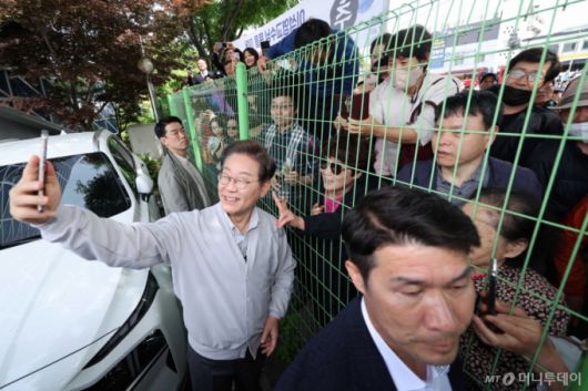 [전주=뉴시스] 민심을 청취하는 '경청 투어'에 나선 이재명 더불어민주당 대선후보가 7일 전북 전주시 완산구 풍남문 인근에서 철조망 너머에 있는 시민들과 셀카를 찍고 있다. 2025.05.07.