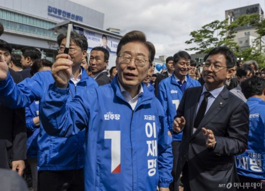 [광주=뉴시스] 조성우 기자 = 이재명 더불어민주당 대선후보가 17일 광주광역시 서구 김대중컨벤션센터 광장에서 열린 집중 유세를 마친 뒤 유세장을 떠나다 시민들의 요청으로 자신의 저서에 서명을 해준 뒤 펜을 들고 주인을 찾고 있다. (공동취재) 2025.05.17. photo@newsis.com /사진=김근수