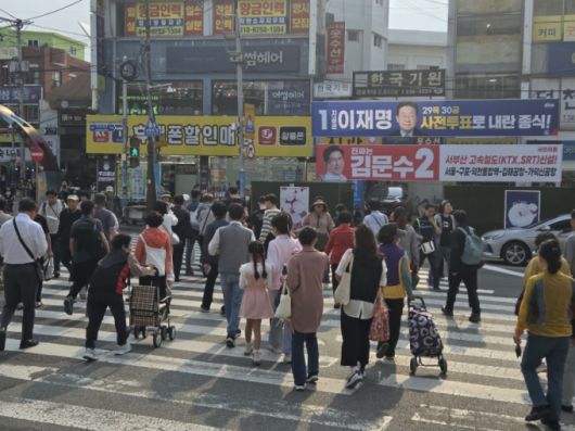 부산 시민들이 이재명·김문수 대선 후보 플래카드 앞 횡단보도를 건너는 모습./사진=유재희 기자.