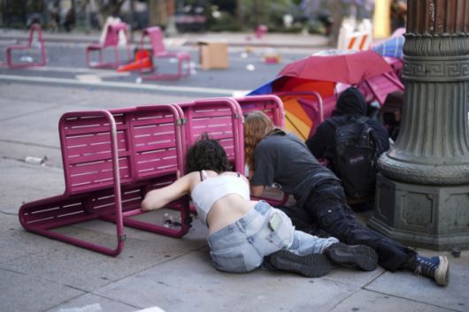 [로스앤젤레스=AP/뉴시스] 8일(현지 시간) 미 캘리포니아주 로스앤젤레스 도심 메트로폴리탄 구치소 인근 101번 고속도로에서 이민세관단속국(ICE)의 불법 이민자 단속 및 체포에 항의하는 시위대가 의자 뒤로 몸을 숨기고 있다. 2025.06.09.