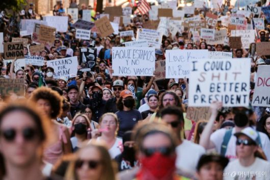 9일(현지시간) 미국 텍사스주 오스틴에서 연방 이민 단속에 반대하는 로스앤젤레스 시위와 연대하는 집회에 참석한 시위대가 다양한 구호를 적은 피켓을 들고 있다./로이터=뉴스1