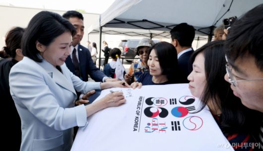 [캘거리=뉴시스]  이재명 대통령 부인 김혜경 여사가 17일(현지 시간) 캐나다 앨버타주 캘거리 한인회관에서 열린 캐나다 서부 동포사회와의 대화를 나누기 전 인사하며 티셔츠에 싸인을 하고 있다. 2025.06.18.