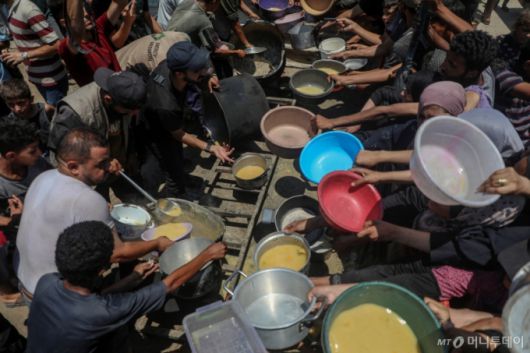 24일(현지 시간) 가자지구 가자시티 자선 급식소에서 팔레스타인 주민들이 구호 음식을 받고 있다. 마무드 아바스 팔레스타인 자치정부 수반은 "가자지구와 요르단강 서안지구에서 이어지는 이스라엘과의 분쟁 속에 팔레스타인인들은 그들 세대 최대의 인도주의적 재앙에 직면해 있다"라며 "이스라엘에 대한 국제사회의 억지 노력이 실패했다"라고 말했다. /신화=뉴시스